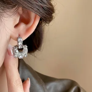Close-up view of elegant U-shaped bag earrings with sparkling zircons worn by model