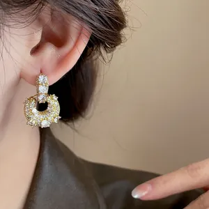 Close-up of gold plated handbag-shaped earrings encrusted with sparkling zircons