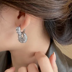 Detail view of elegant silver U-shaped bag earrings with shimmering zirconia on ear