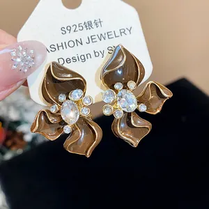 Close-up of Maillard brown flower stud earrings with sparkling rhinestone centers.