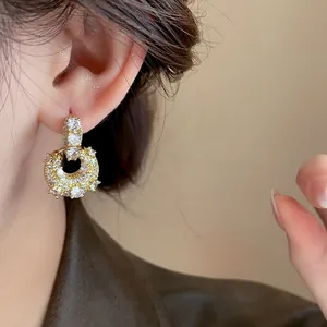 Close-up detail of elegant gold-plated zircon hoop earrings worn by a model showing sparkle