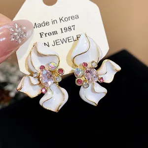 Close-up of elegant flower earrings with pink crystal centers and white enamel petals