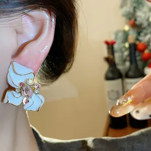 Detailed view of an elegant white enamel flower stud earring with a pink gemstone