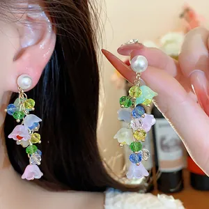 Close-up of floral tassel earrings with colorful resin flowers, crystals, and pearls