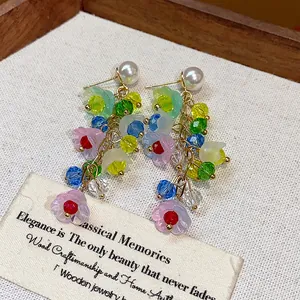 Detail view of colorful resin flower tassel earrings with crystals and white pearl studs