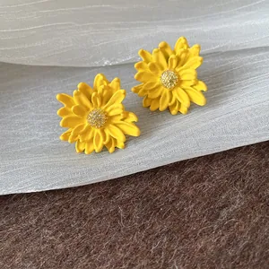 Close-up of yellow flower stud earrings with sparkling stamen and a matte finish.