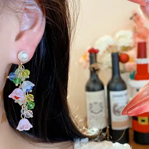 Close-up of resin flower tassel earrings with pearls and colorful beads worn on ear
