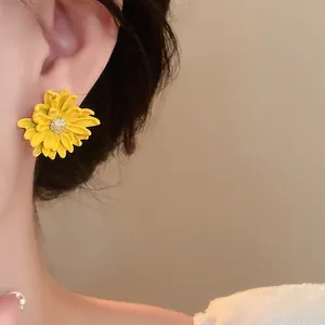 Close-up of a vibrant yellow sunflower earring on a model's ear for a sweet look
