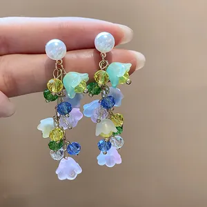 Detailed view of colorful resin flower tassel earrings with pearls and faceted beads.