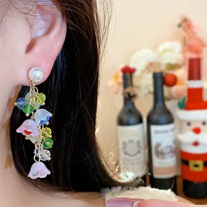 Close-up detail of colorful resin flower tassel earrings with pearl studs worn on ear