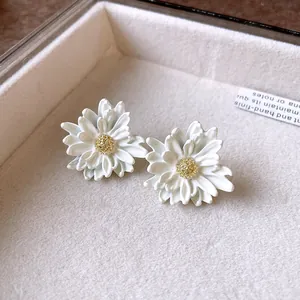 Detailed macro shot of white daisy flower earrings with gold pistil centers