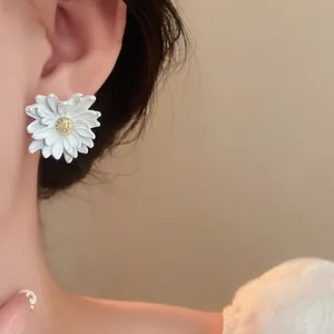 Detailed view of a delicate white daisy flower earring with silver pin worn on ear