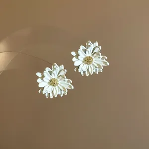 Detailed view of elegant white daisy flower stud earrings with golden stamen centers