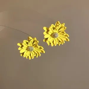 Close-up detail of yellow chrysanthemum flower stud earrings with sparkly centers.
