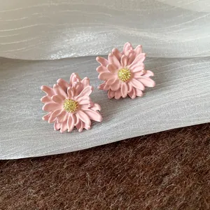 Detailed macro view of pink floral stud earrings with textured golden centers