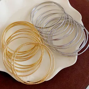 Detailed macro view of multilayer gold and silver metal bangles featuring smooth and textured finishes