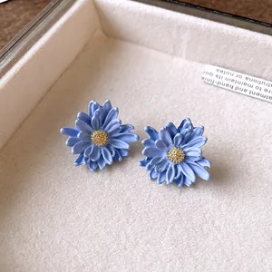 Detailed macro view of matte blue daisy flower earrings with textured golden centers