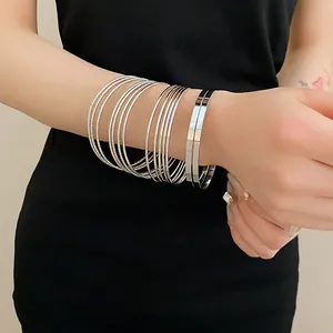 Detailed close-up showing stacked minimalist silver metal bangles worn on a wrist
