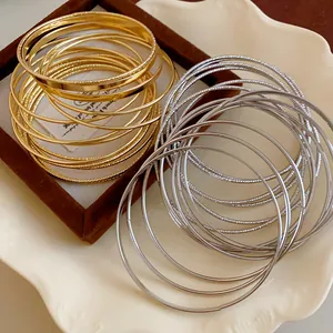 Detail showing multilayer metal bangles in polished gold and silver finishes.