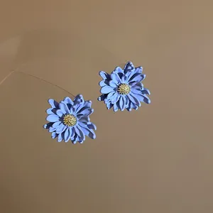 Detailed view of matte blue floral earrings with textured golden stamens