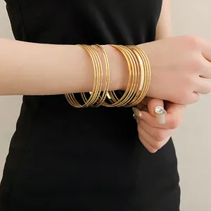 Detailed close-up view of stylish multi-layer gold metal bangles worn on a model's wrist.