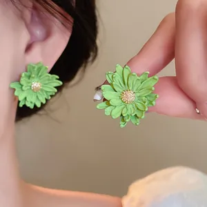 Macro detail of sweet green floral stud earrings featuring refined gold centers worn on model