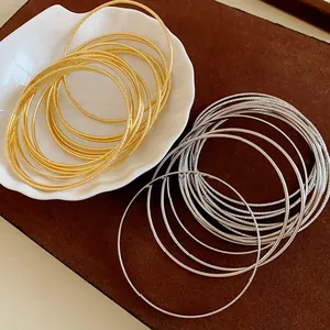 Close-up detail of elegant gold and silver multi-layer metal bangles displayed on a shell dish