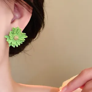 Detailed close-up showing a vibrant green flower earring with a sparkling golden stamen