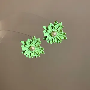 Macro view of light green flower stud earrings featuring textured sparkly flower cores