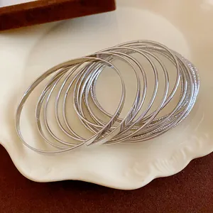 Close-up of silver-colored multi-layer metal bangles with textured and polished finish