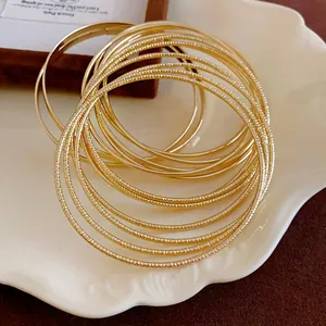 Detailed close-up of multi-layer gold metal bangles with smooth and textured finishes.