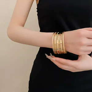 Close-up view of stylish multi-layer gold plated metal bangles on a female wrist