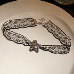 Detail shot of black lace choker necklace with a sparkling rhinestone star pendant.