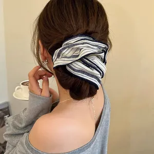Detail shot of a striped fabric hair scrunchie styled in a low bun on an Asian model.