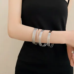 Detail of multi-layer silver metal bangles styled on a model arm for fashion