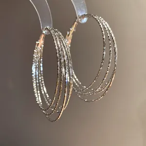 Detailaufnahme der schimmernden, mehrlagigen silbernen Creolen mit Textur für Damen.