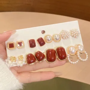 Close-up of elegant six-pair earring set featuring pearls and red enamel details