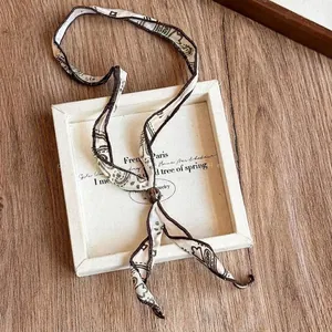 Detailed macro view of the paisley print fabric scarf necklace with brown bead accent