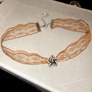 Close-up of elegant orange lace choker necklace featuring a sparkling rhinestone star pendant