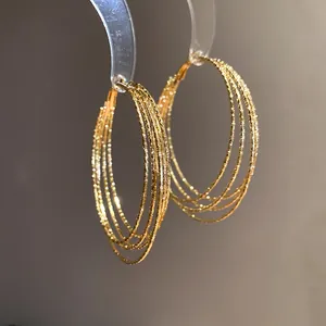 Detail von Vintage-Goldohrringen mit mehreren Schichten und funkelnder Textur