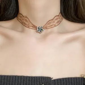 Close-up detail of a vintage brown lace choker with a shiny rhinestone star pendant.