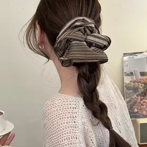 Detailed view of an oversized striped retro hair scrunchie on a braided ponytail style.