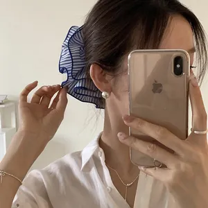 Close-up detail of a blue and white striped oversized fabric scrunchie worn in hair