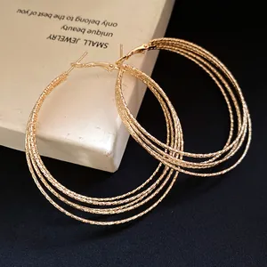 Detailaufnahme von goldfarbenen mehrlagigen Creolen mit funkelndem, strukturiertem Finish.