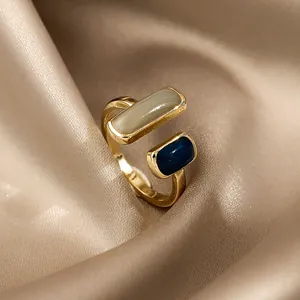 Vista dettagliata di un anello aperto geometrico con accenti di smalto beige e blu navy