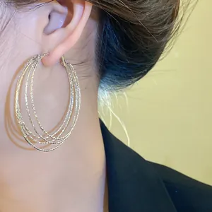 Detailansicht von eleganten mehrlagigen silbernen Metall-Creolen am Ohr des Models