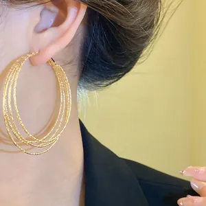 Nahaufnahme von eleganten goldenen mehrlagigen strukturierten Creolen an einem Model
