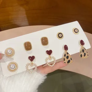 Detailed view of six pairs of elegant pearl and heart-shaped leopard print earrings