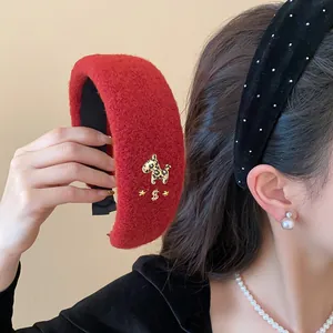Nahaufnahme eines dicken, roten beflockten Stirnbands mit goldenem Pferdchen und Sternen