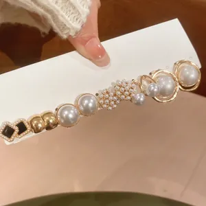 Close-up of elegant gold hair clip with white pearls and black square accents